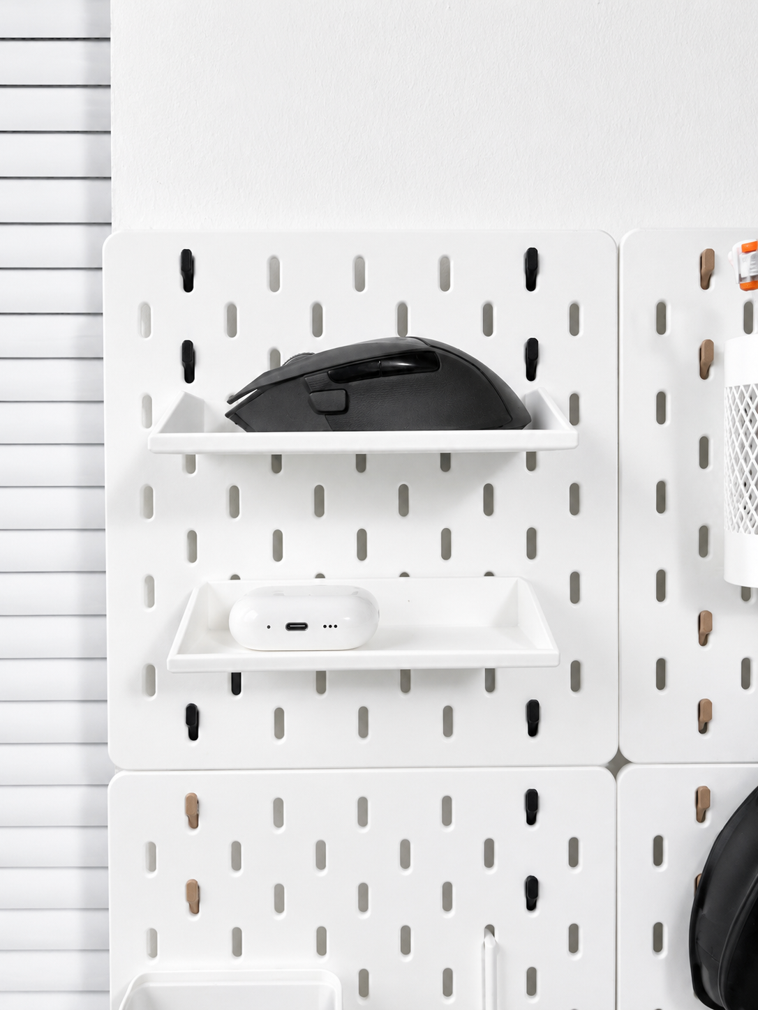 IKEA SKÅDIS pegboard shelf used as a desk organizer tray for a mouse, earbuds, and small office accessories